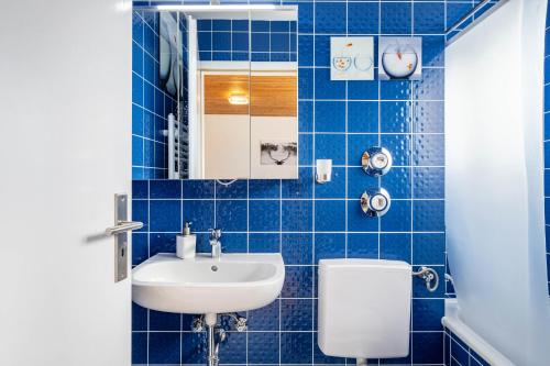 a blue tiled bathroom with a sink and a toilet at Schwarzwaldblick D App 10 mit Pool in Schönwald