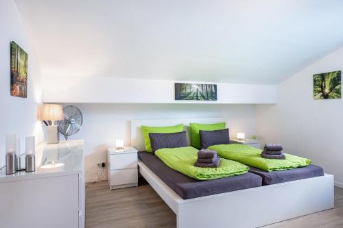 a bedroom with a bed with green pillows at Schwarzwaldblick D App 10 mit Pool in Schönwald