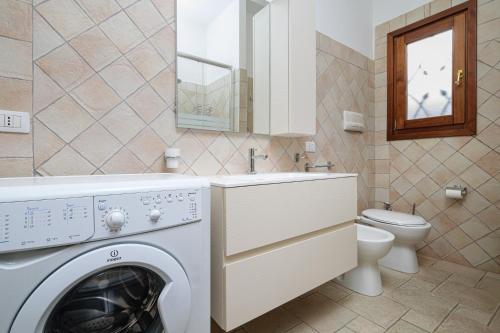a bathroom with a washing machine and a toilet at Trilo La Rosa in Monte Petrosu