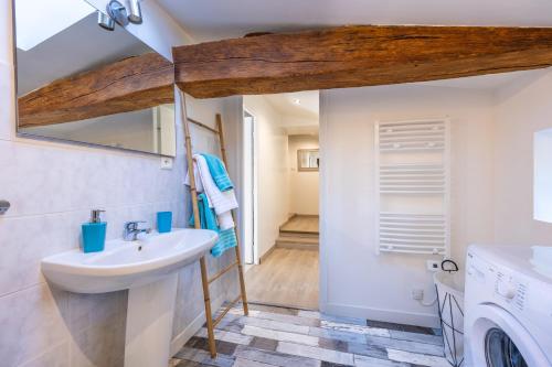 a bathroom with a sink and a washing machine at Gite Augustine Aux Charmes D'antan in Sevremont