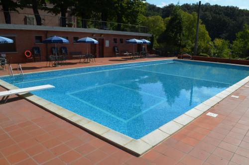 a large blue swimming pool with tables and umbrellas at Agriturismo Le Case di San Vivaldo in Montaione