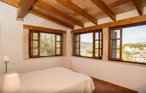 a bedroom with windows and a bed with white sheets at Can Baixo in Port de Soller