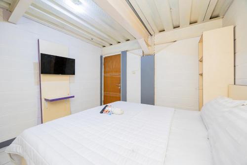 a bedroom with a large white bed and a tv at Simple Hotel Bogor RedPartner in Bogor