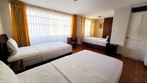 a hotel room with two beds and a window at Hotel Palmeras Tacna in Tacna