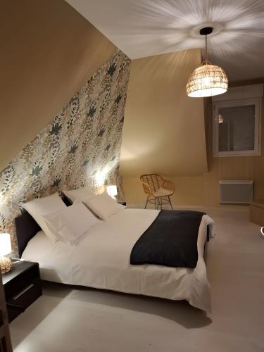 a bedroom with a large white bed and a chandelier at Chambre D'hôte - La Capucine in Bazouges
