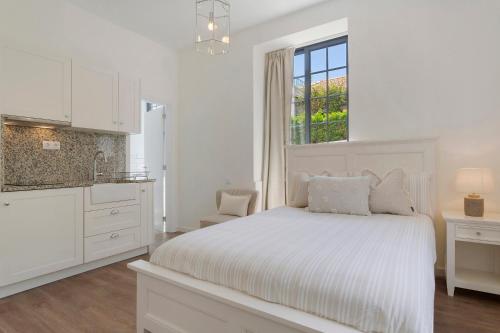 a white bedroom with a bed and a window at Vila Francisco in Funchal
