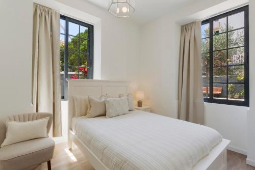 a white bedroom with a bed and a chair at Vila Francisco in Funchal