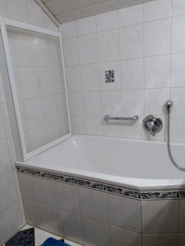a bath tub in a bathroom with white tiles at Ferienwohnung Waldkäuzle in Lenzkirch