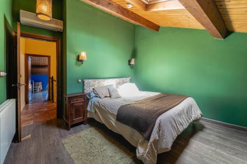 a green bedroom with a bed and a wooden ceiling at El Palomar De La Cuesta in Lerma