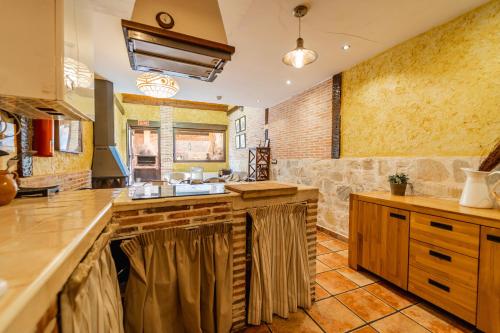 a large kitchen with wooden counters and a stone wall at El Palomar De La Cuesta in Lerma