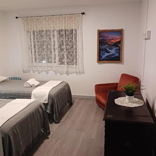 a room with two beds and a chair and a window at Casa Tibagota in São Brás de Alportel