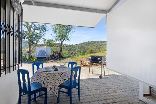 a patio with a table and chairs and a grill at Casa Tibagota in São Brás de Alportel