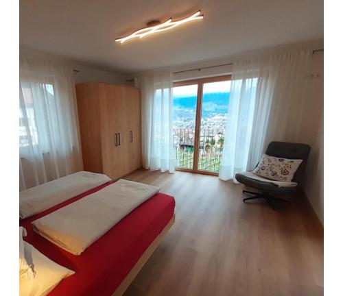 a bedroom with a bed and a window and a chair at Fröhlichhof Wohnung Apfelblüte in Lagundo