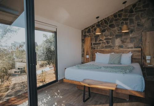 a bedroom with a bed and a stone wall at Cabañas by 7 Valles in Valle de Guadalupe