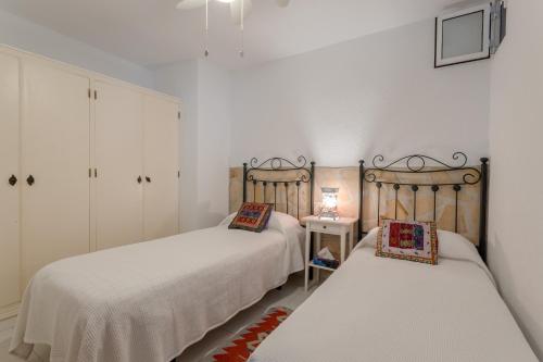 two beds in a room with white walls at Mi Casa in Caleta De Velez