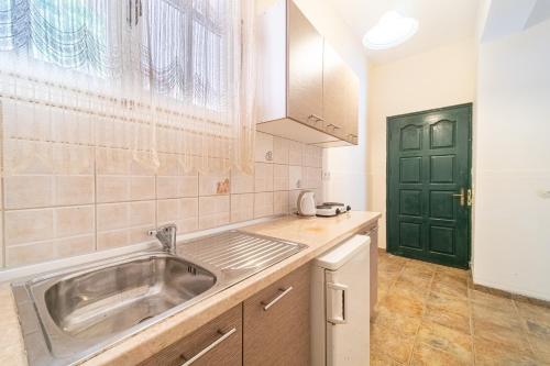 a kitchen with a sink and a green door at Arianna Studio 15 in Paleokastritsa
