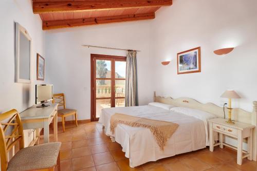 a bedroom with a bed and a desk and a window at Casa Tolo in Son Servera