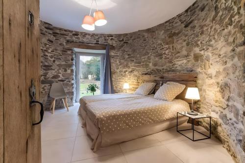 a bedroom with a bed and a stone wall at Gîte Du Moulin De La Violaye in Fay-de-Bretagne