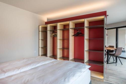 a bedroom with a bed and a red wall at Aumia Apartment Rubin in Völs am Schlern