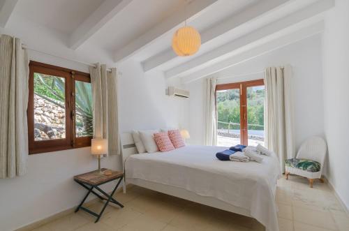 a white bedroom with a bed and a window at Villa Diani in Binibeca