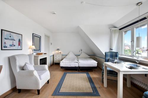 a white living room with a table and a chair at Ferienwohnung Haus Lazy Dolphin in Rantum