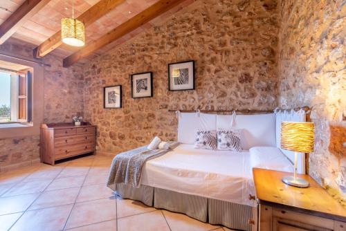 a bedroom with a bed and a stone wall at Son Xigala in Manacor