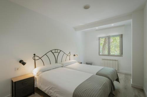 a white bedroom with a large bed and a window at Mónaco in Valladolid