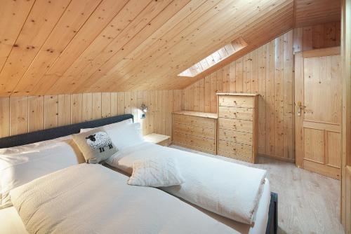 a bedroom with a large white bed in a wooden ceiling at Appartamento Primavera 3 in Moena