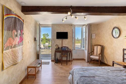 a bedroom with a bed and a desk and a tv at Chambre d'Hotes La Roseraie in Saint-Émilion
