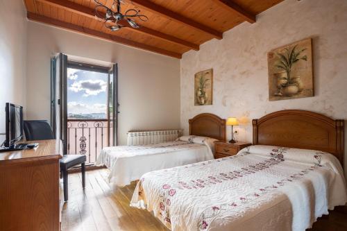 a bedroom with two beds and a desk and a television at Aldea Salguero in Albandi