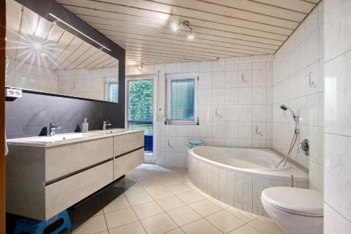 a bathroom with a tub and a sink and a toilet at Ferienwohnung Annette in Gomadingen