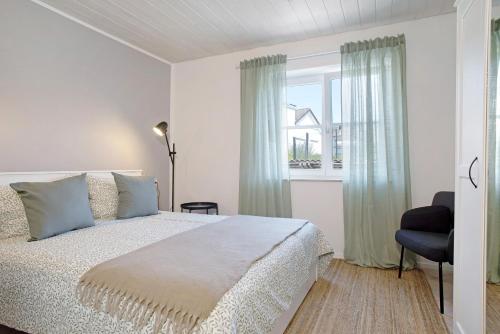 a white bedroom with a bed and a window at Karlotta in Eriskirch