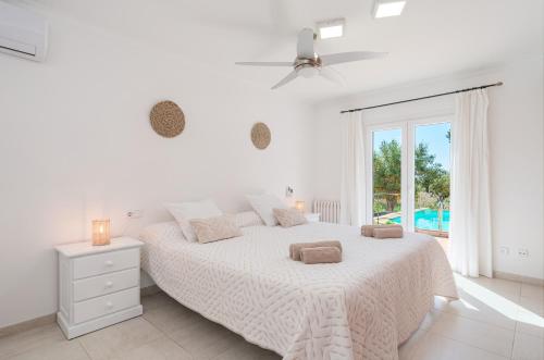 a white bedroom with a large bed and a window at Ca na Barons in Bunyola