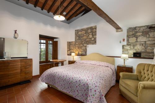 a bedroom with a bed and a couch and a television at La Petrosa in Radda in Chianti