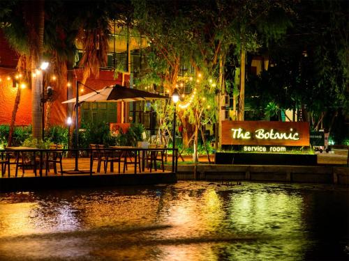 a restaurant with tables and an umbrella at night at Botanic Service Room at Impact Muangthongthani - SHA Certified in Nonthaburi
