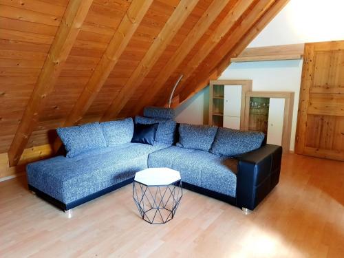 a blue couch in a room with a wooden ceiling at Ferienwohnung Schwarzwaldfeder in Todtnau