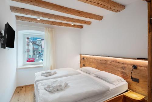 a bedroom with a white bed with a wooden headboard at Casa Patty Moena in Moena