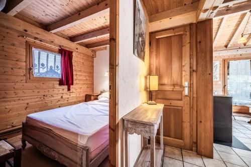 a bedroom in a log cabin with a bed and a table at Chalet 7p Confort - Le refuge in Verchaix