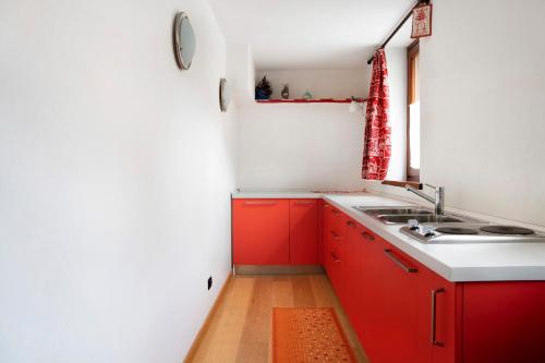a kitchen with red cabinets and a sink at Chalet Provenzale Trilocale in Acceglio