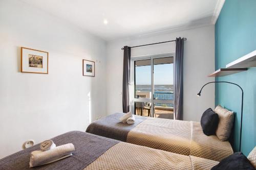 a bedroom with two beds and a view of the ocean at Duplex Apartamento Tartaruga in Santa Luzia