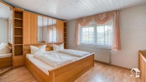 a bedroom with a bed and a large window at Ferienhaus Mengelberg in Roschbach
