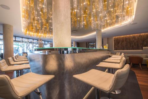 a restaurant with a bar with chairs and chandeliers at Best Western Premier Hotel de la Paix in Reims