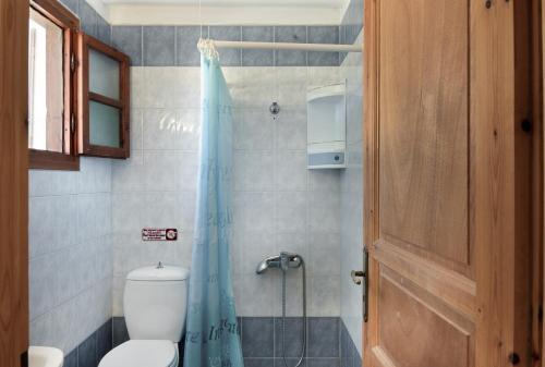 a bathroom with a toilet and a blue shower curtain at Studios Asterias 3 in Astypalaia