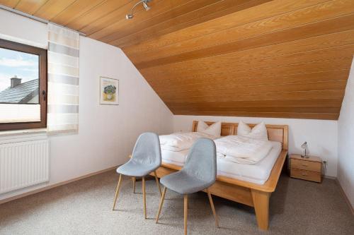 a small bedroom with a bed and two chairs at Am Pön - Ferienwohnungen in Medebach