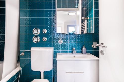 a blue tiled bathroom with a toilet and a sink at Schwarzwaldblick C App 2 mit Pool in Schönwald