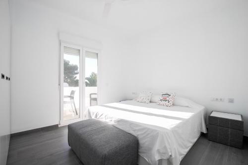 a white bedroom with a bed and a chair at Apartamento Marei 2 in Cala Blanca