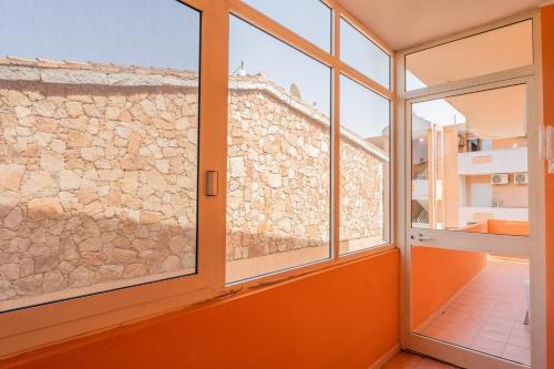 an orange room with windows and a stone wall at Colombo Rooms in Sestu