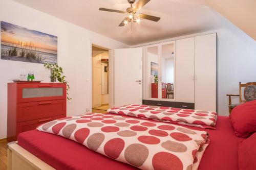 a bedroom with a red bed and a dresser at Ferienwohnung Schürer in Meckenbeuren