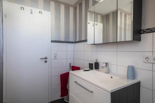 a white bathroom with a sink and a mirror at Ferienwohnung Schürer in Meckenbeuren