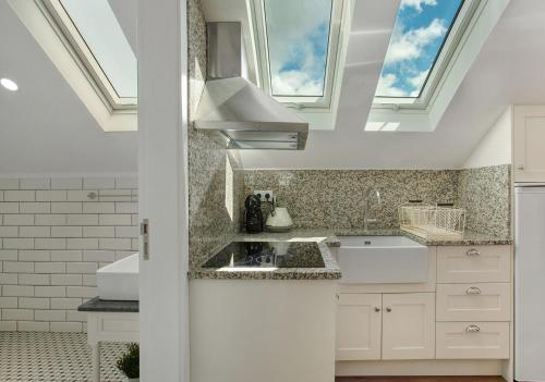 a kitchen with white cabinets and a skylight at Vila Francisco in Funchal